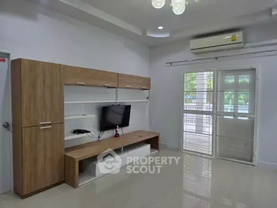 Modern living room with sleek entertainment unit and air conditioning, featuring large windows for natural light.