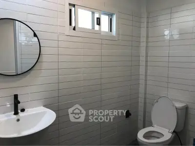 Modern bathroom with sleek white tiles and round mirror