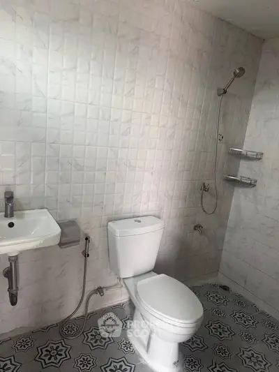 Modern bathroom with stylish tiles and sleek fixtures, featuring a shower and toilet.