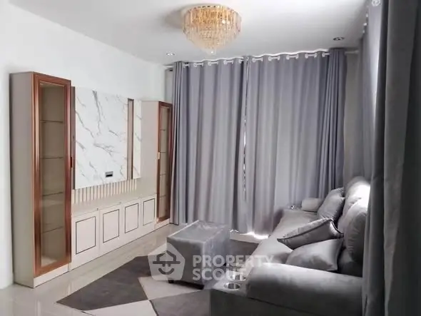 Elegant living room with plush gray sofa, marble accent wall, and luxurious chandelier.