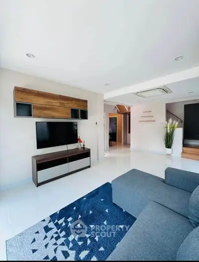 Modern living room with sleek furniture and stylish decor, featuring a cozy gray sofa and wall-mounted TV.