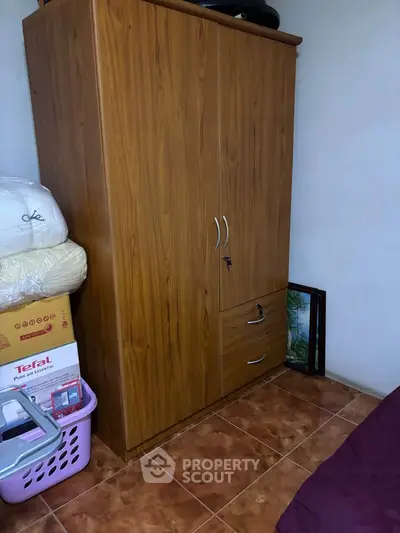 Cozy bedroom with wooden wardrobe and tiled flooring, perfect for compact living spaces.
