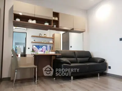 Modern living room with sleek black sofa, stylish shelving, and elegant dining area in contemporary apartment.