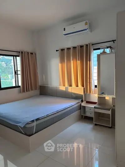 Modern bedroom with natural light, featuring a comfortable bed and air conditioning.