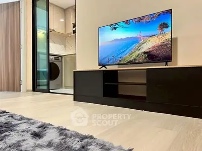 Modern living room with sleek TV setup and view into stylish kitchen