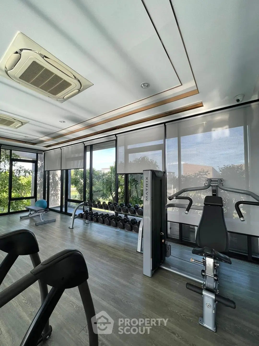 Modern gym with large windows and fitness equipment in a bright, airy space.
