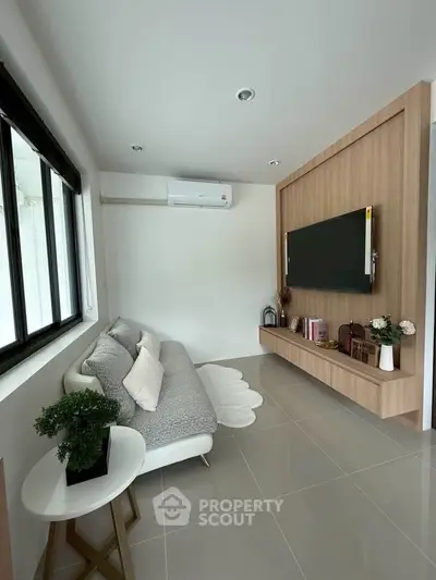 Modern living room with sleek design, featuring a wall-mounted TV, cozy sofa, and stylish decor.