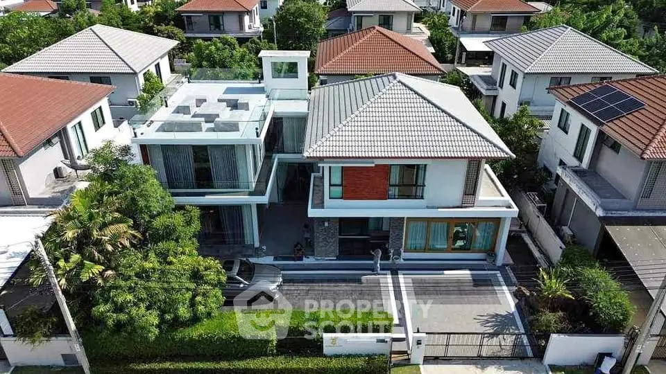 Stunning aerial view of modern two-story house with spacious driveway and lush greenery.
