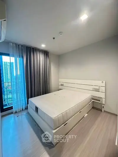 Modern bedroom with large window and city view, featuring sleek design and natural light.
