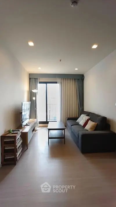 Modern living room with cozy sofa and natural light from balcony, perfect for relaxation.