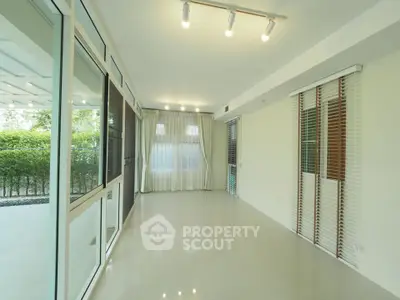 Spacious sunlit room with large windows and modern lighting, perfect for versatile living space.