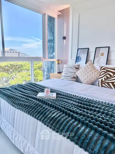 Luxurious bedroom with large windows offering stunning city views and elegant decor.