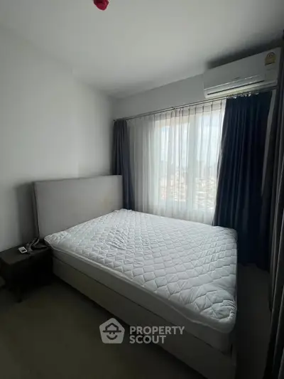 Cozy bedroom with modern decor and large window offering city views, perfect for urban living.