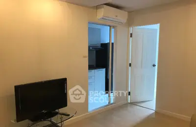 Cozy living room with TV and air conditioning, adjacent to a modern kitchen.
