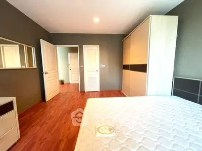 Spacious bedroom with wooden flooring and large wardrobe in modern apartment.
