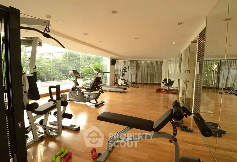 Spacious gym with modern equipment and large windows offering a serene view.