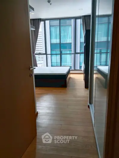 Modern bedroom with large windows and wooden flooring in urban apartment