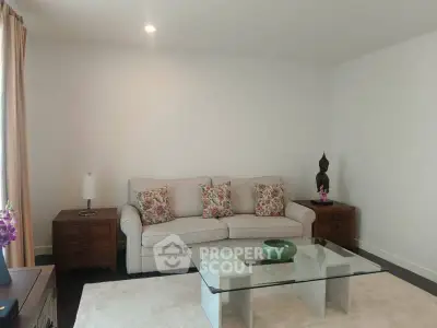 Elegant living room with cozy sofa, glass coffee table, and stylish decor accents.