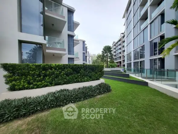 Modern apartment complex with lush green landscaping and glass balconies