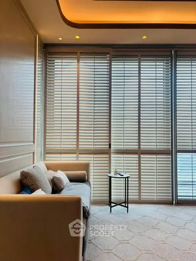 Elegant living room with modern sofa and floor-to-ceiling windows with blinds, creating a cozy ambiance.