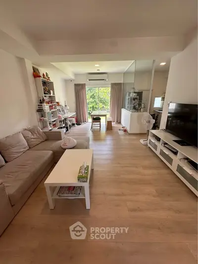 Spacious living room with modern decor and large window offering natural light and garden view.