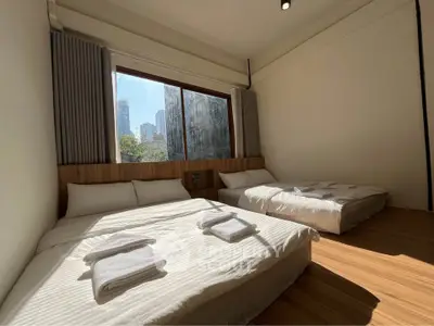 Spacious bedroom with two beds and large window offering city view, perfect for urban living.
