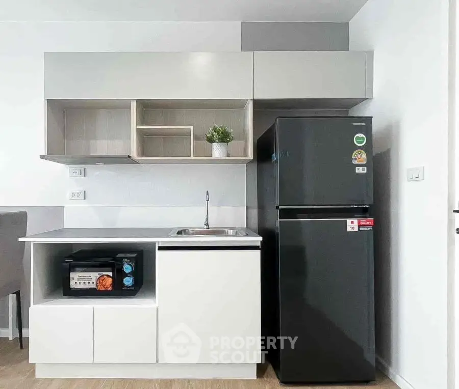 Modern compact kitchen with sleek cabinets and appliances in a stylish apartment.