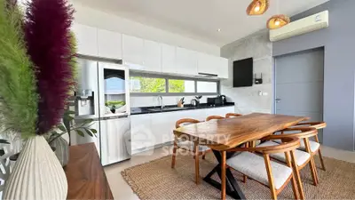 Modern kitchen with sleek design, wooden dining table, and stainless steel appliances.