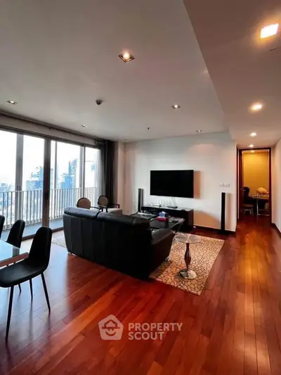 Spacious living room with hardwood floors and city view balcony in modern apartment.