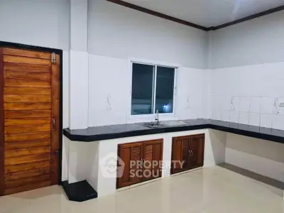 Spacious kitchen with sleek countertops and wooden cabinetry, perfect for culinary enthusiasts.