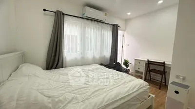Cozy bedroom with natural light, featuring a comfortable bed and a study desk.