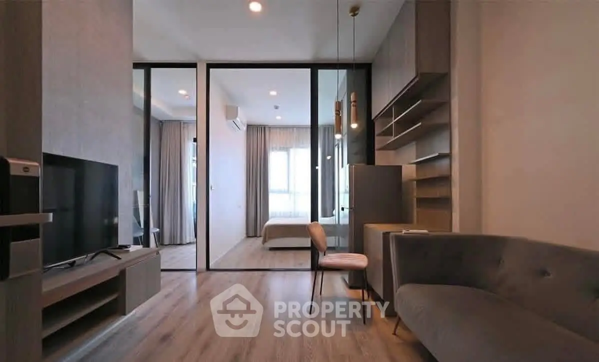 Modern living room with sleek design and open layout, featuring a cozy sofa and large TV.