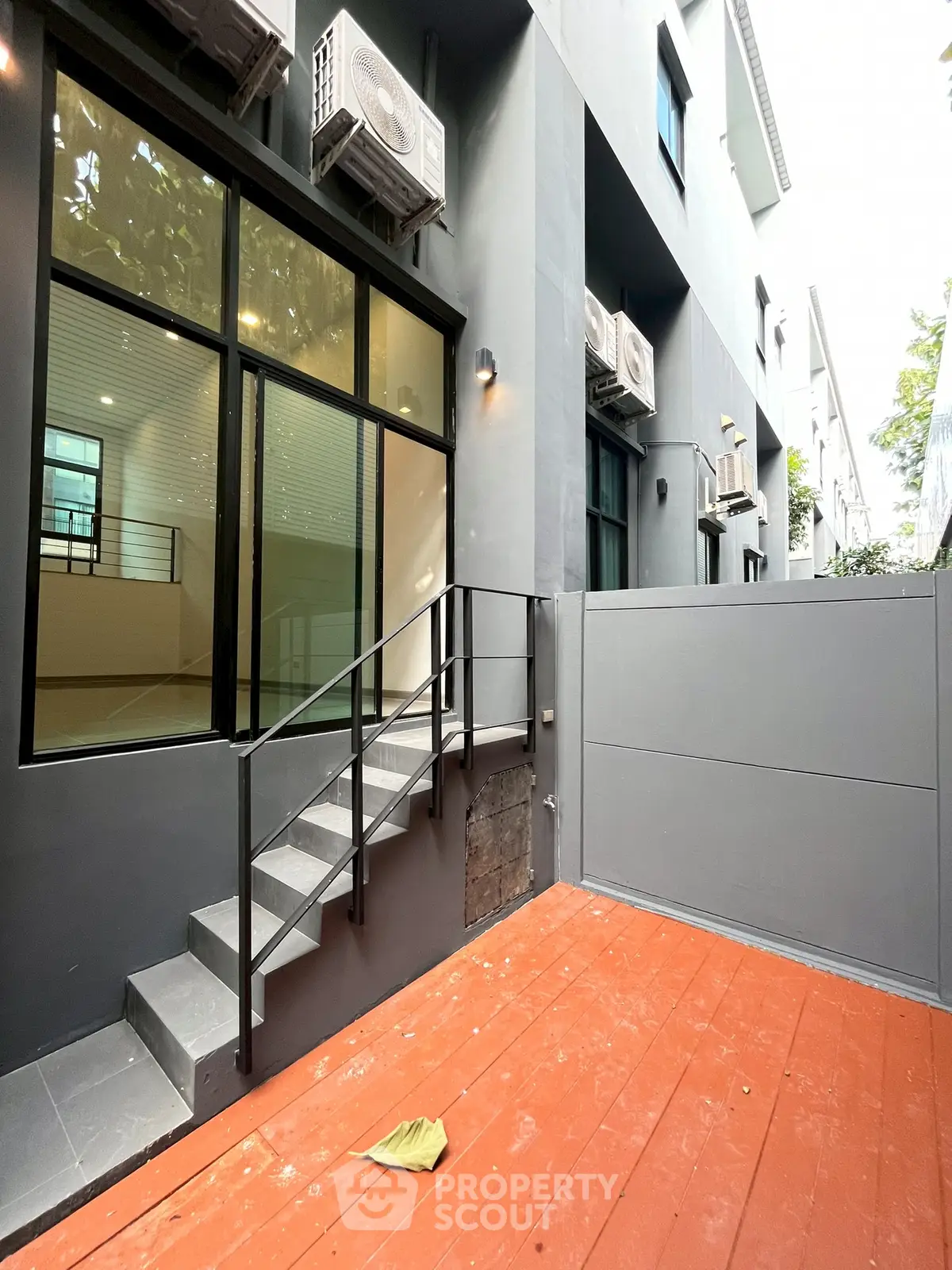 Modern exterior with sleek design and air conditioning units, featuring a small staircase and patio area.