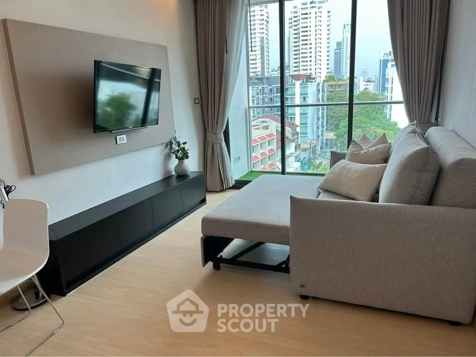 Modern living room with sleek furniture and city view from large windows.