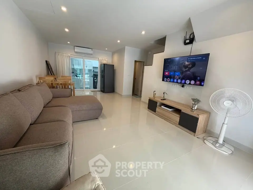 Spacious modern living room with sleek furniture and large TV, perfect for relaxation.
