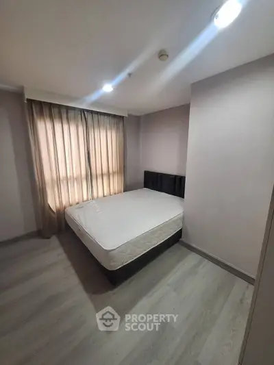 Spacious bedroom with natural light and modern flooring in a stylish apartment.
