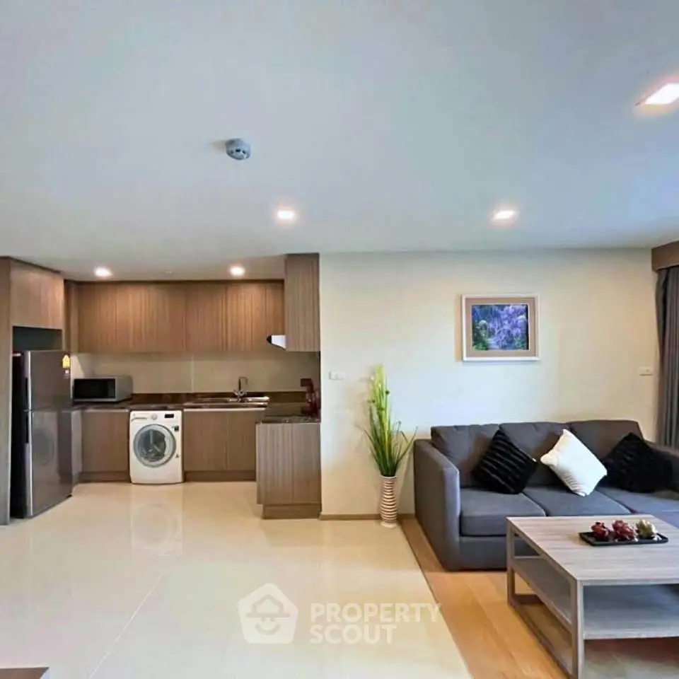 Modern open-plan living room with kitchen, featuring sleek appliances and stylish decor.