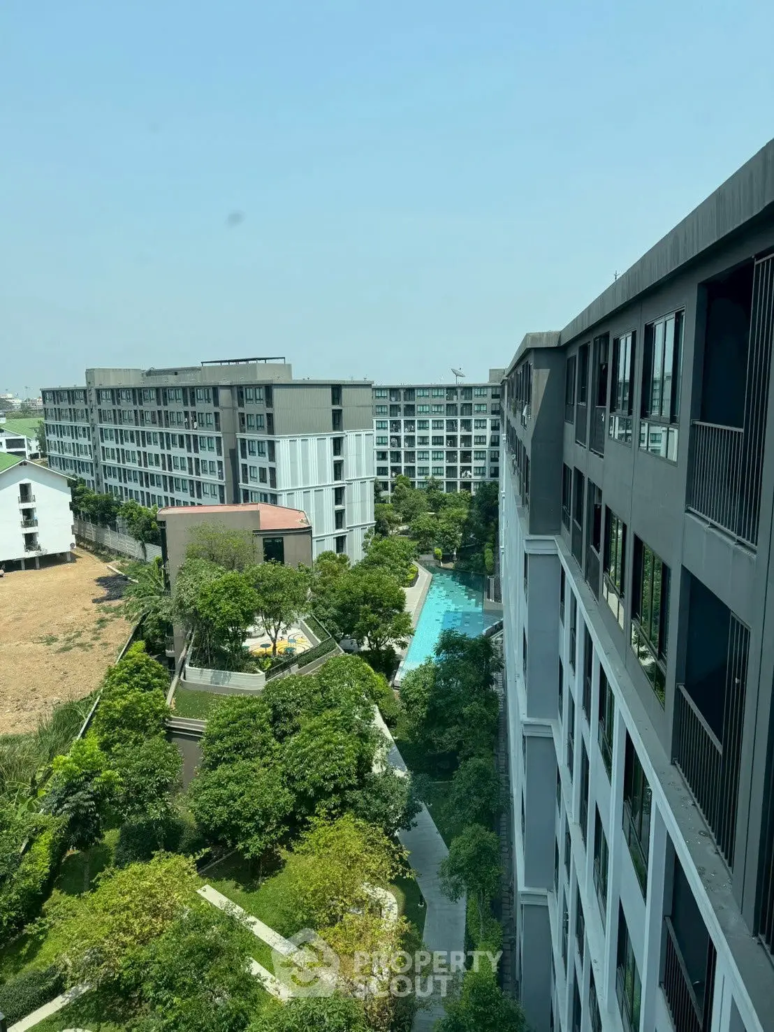 Modern apartment complex with lush greenery and swimming pool view