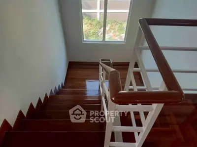 Elegant wooden staircase with natural light from window, perfect for modern homes.