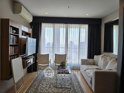 Charming living room with cozy sofa, elegant rug, and natural light from large windows, perfect for relaxation.