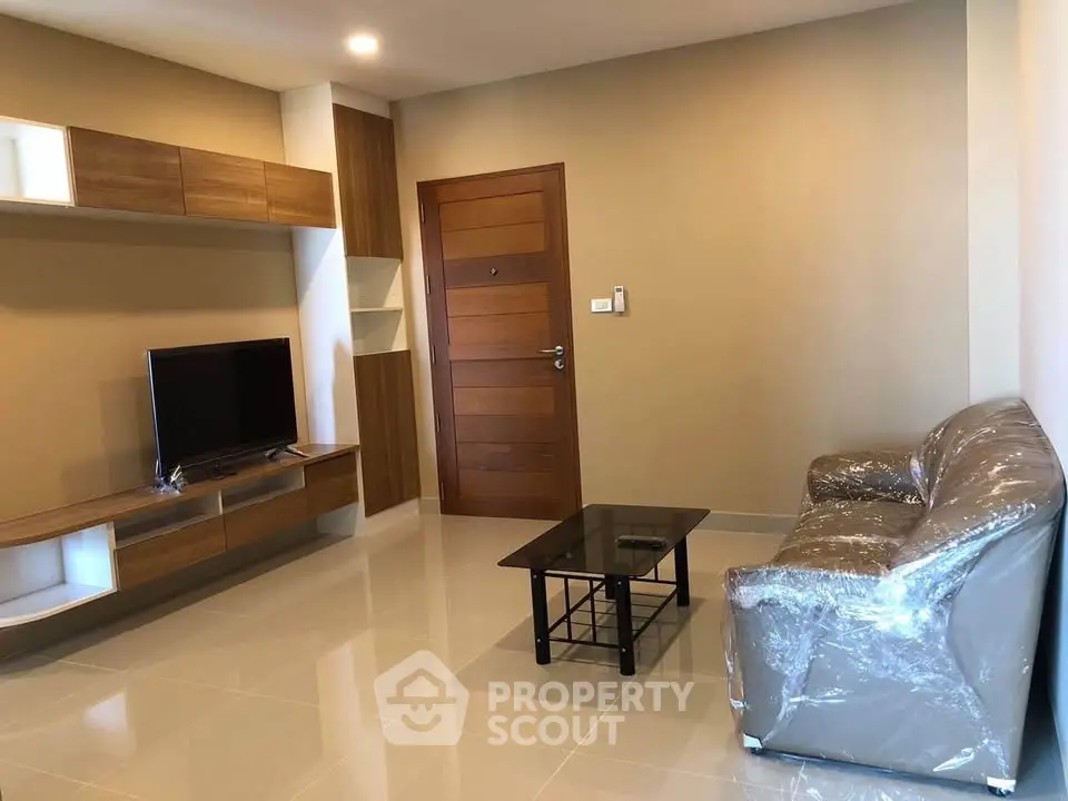Modern living room with sleek furniture and wall-mounted TV in a cozy apartment.