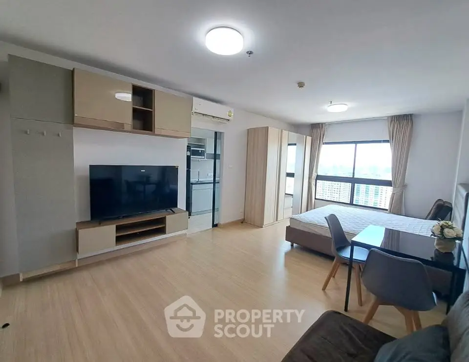 Modern studio apartment with open layout, featuring a cozy living area, dining space, and large window with city view.
