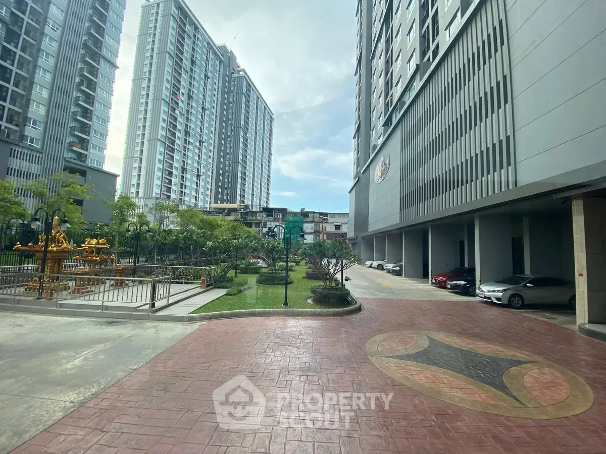 Modern high-rise apartment complex with landscaped garden and parking area.