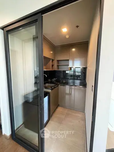 Modern compact kitchen with sleek cabinetry and glass sliding door