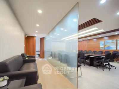 Modern office space with sleek glass partition and stylish conference room.
