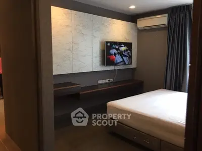Modern bedroom with wall-mounted TV and air conditioning in stylish apartment.