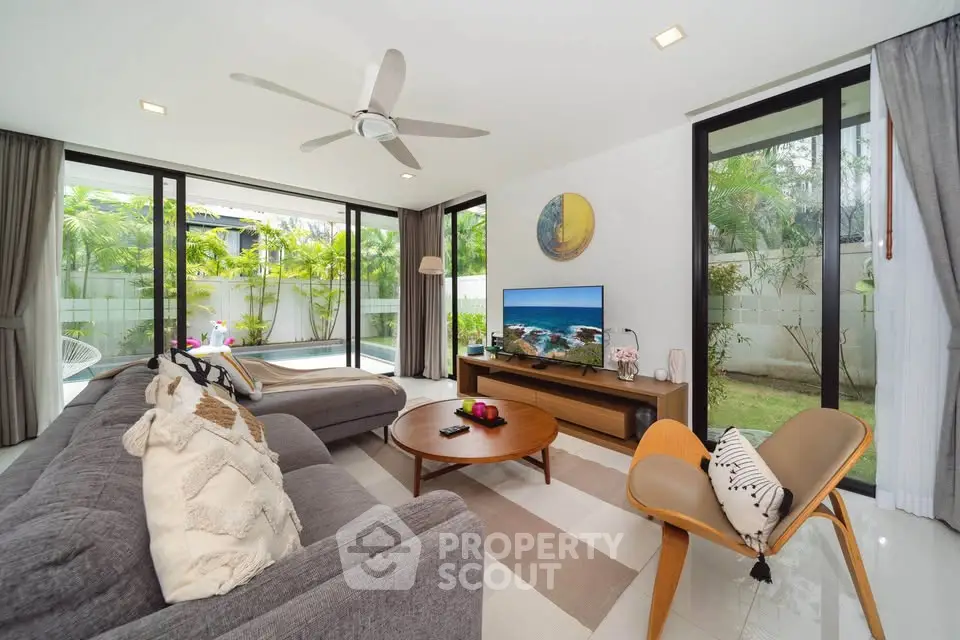 Spacious modern living room with large windows and garden view, featuring stylish furniture and decor.