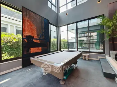 Luxurious modern living room with pool table and large windows offering garden views.