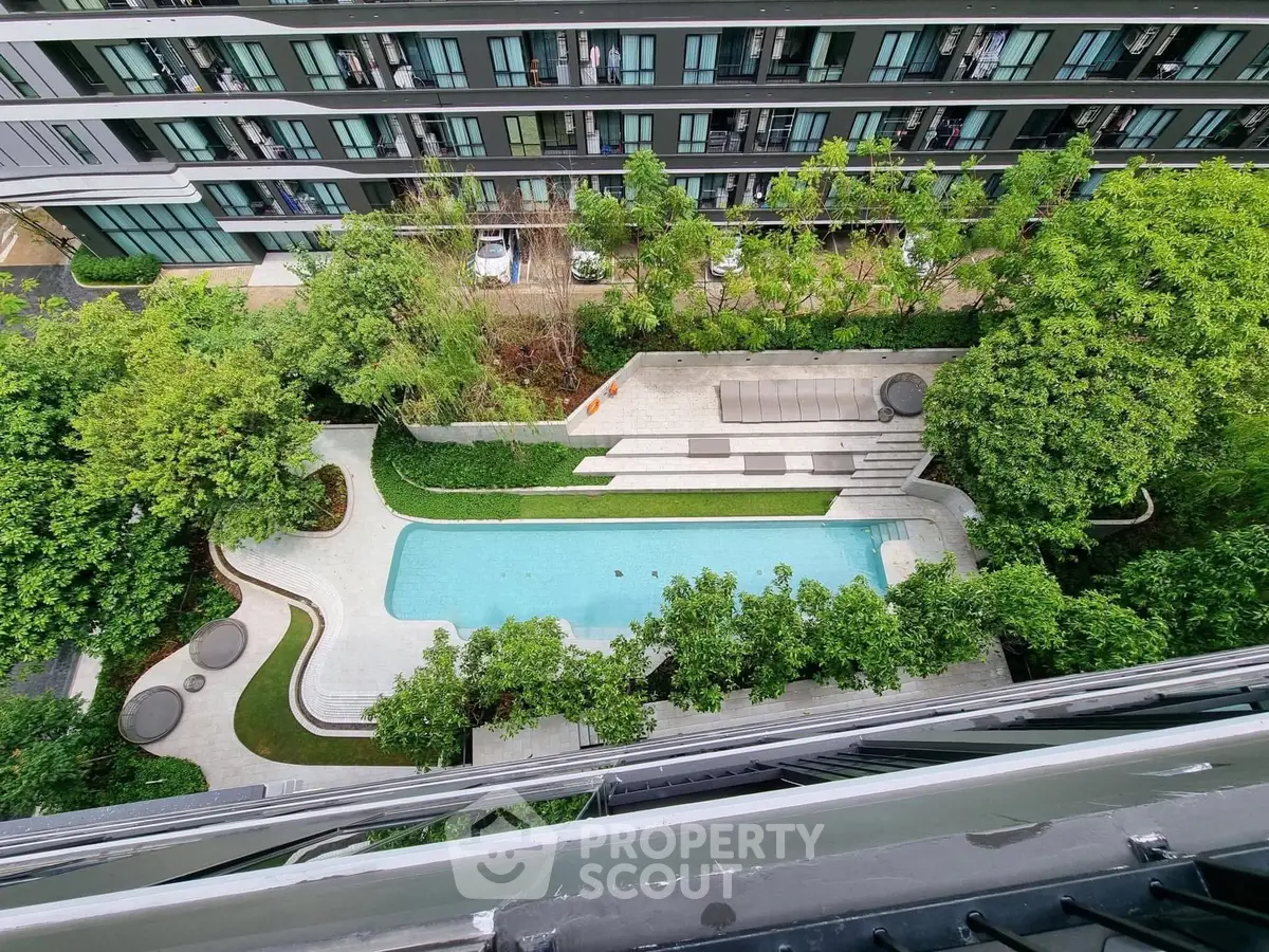 Stunning aerial view of modern apartment complex with lush greenery and inviting swimming pool.