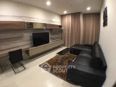Modern living room with sleek black leather sofa and wall-mounted TV